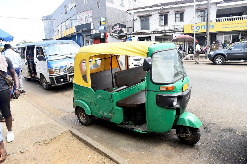 Un Tricycle disputant la chaussée avec des taxis traditionnels au niveau d’Awendjé. © Jocelyn Abila